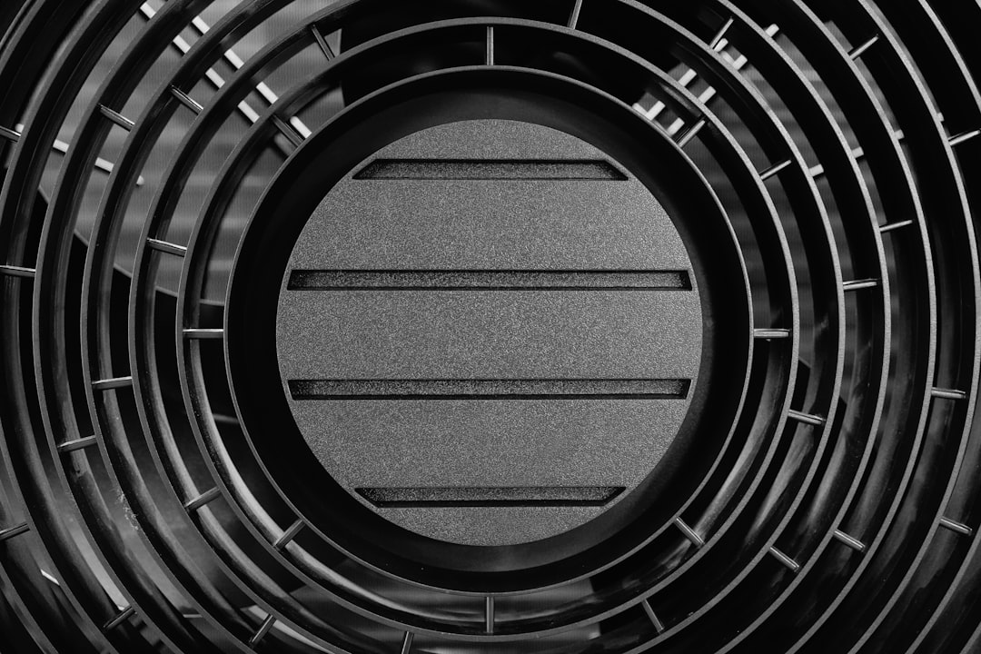 Close-up of a black circular grate with horizontal slats.