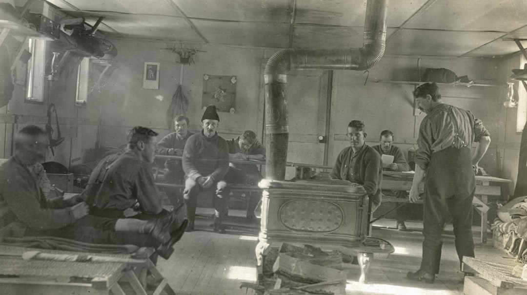 Men gathered inside a rustic room with a stove.