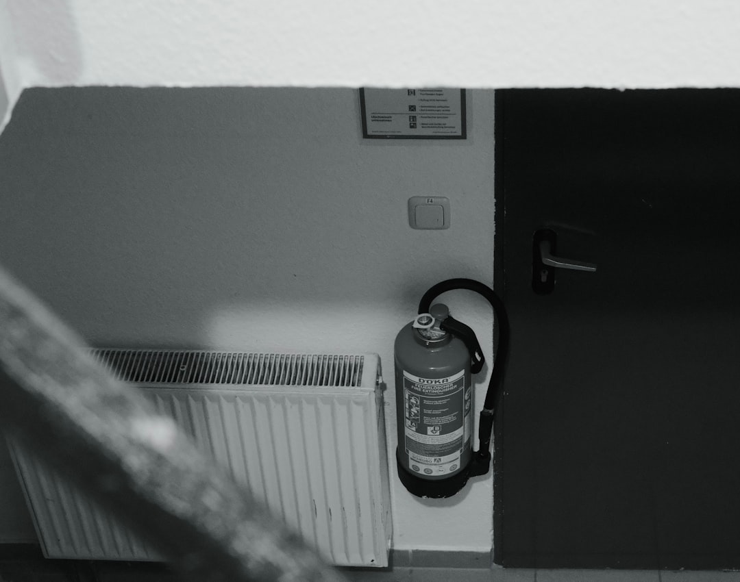 Fire extinguisher mounted on wall next to radiator.