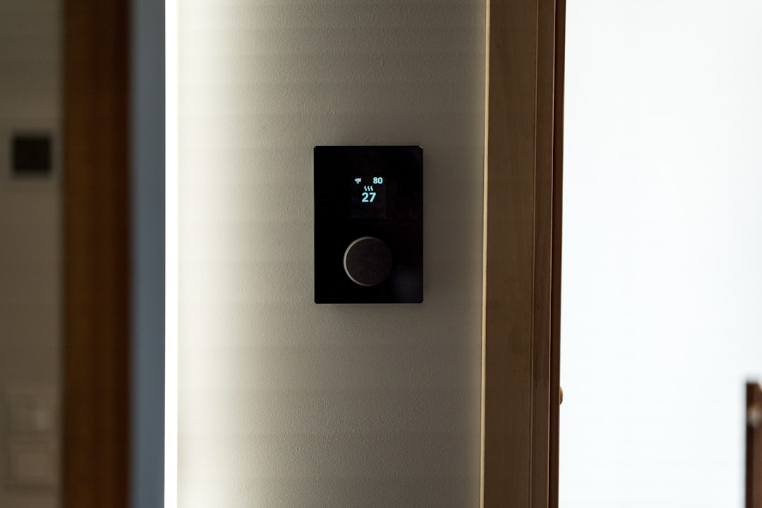 A modern black thermostat mounted on a wall.