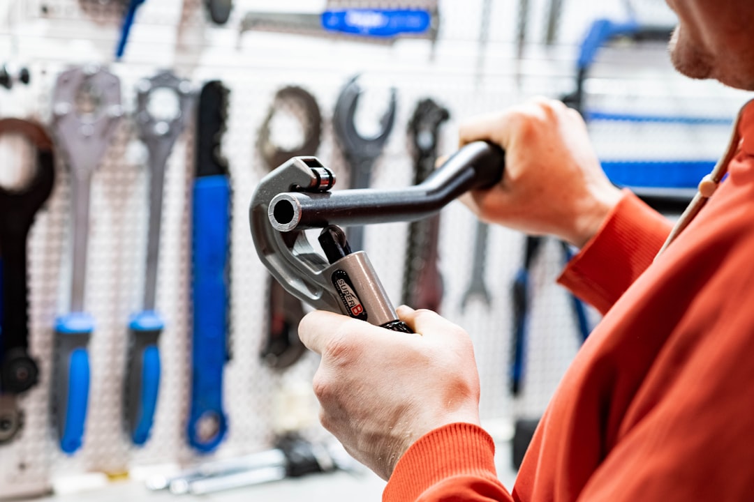 a man holding a wrench in front of a wall of tools