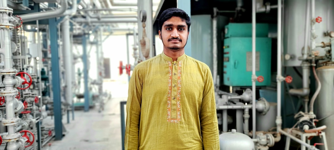 man in yellow long sleeve shirt wearing black cap standing near green building during daytime